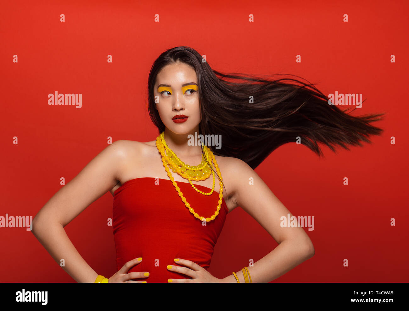 Jolie femme avec étape élégant composent et les cheveux volant sur fond  rouge. Modèle féminin asiatique avec les créateurs de maquillage et  accessoires Photo Stock - Alamy