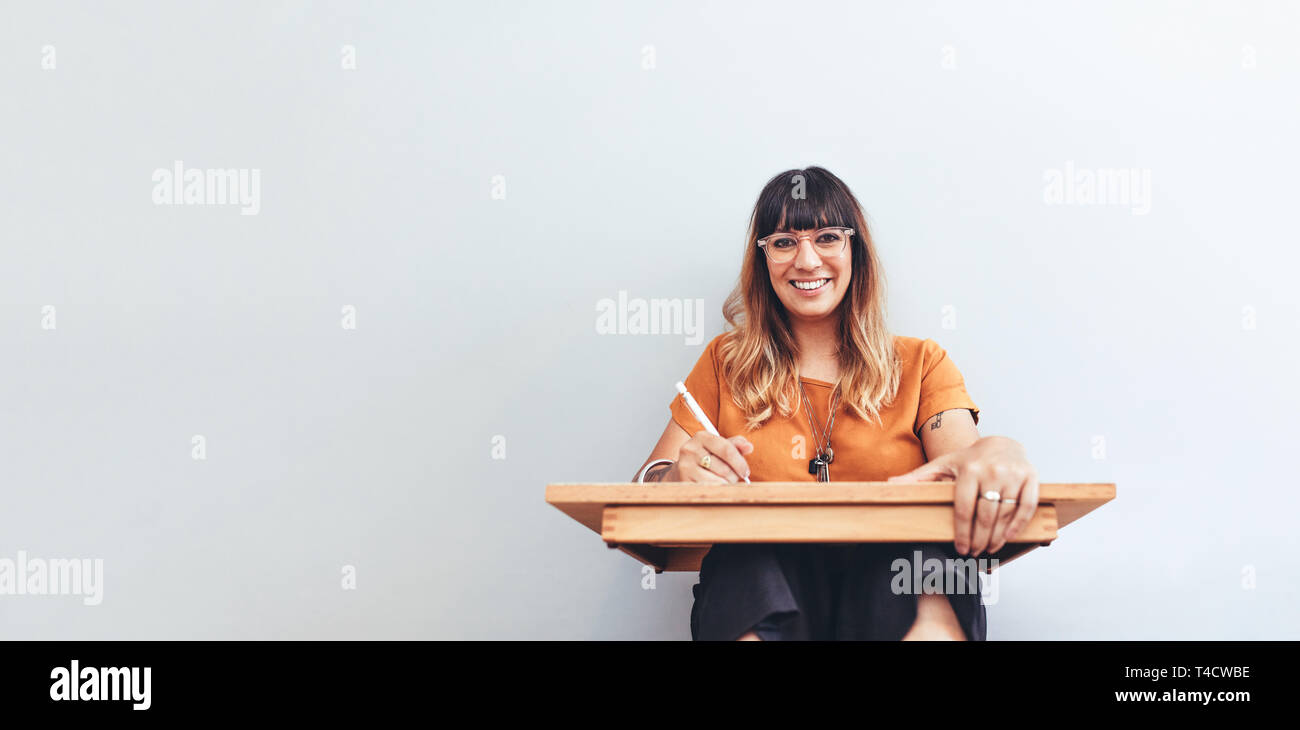 Smiling woman sitting avec une feuille de faire un croquis. L'artiste féminine une illustration. Banque D'Images