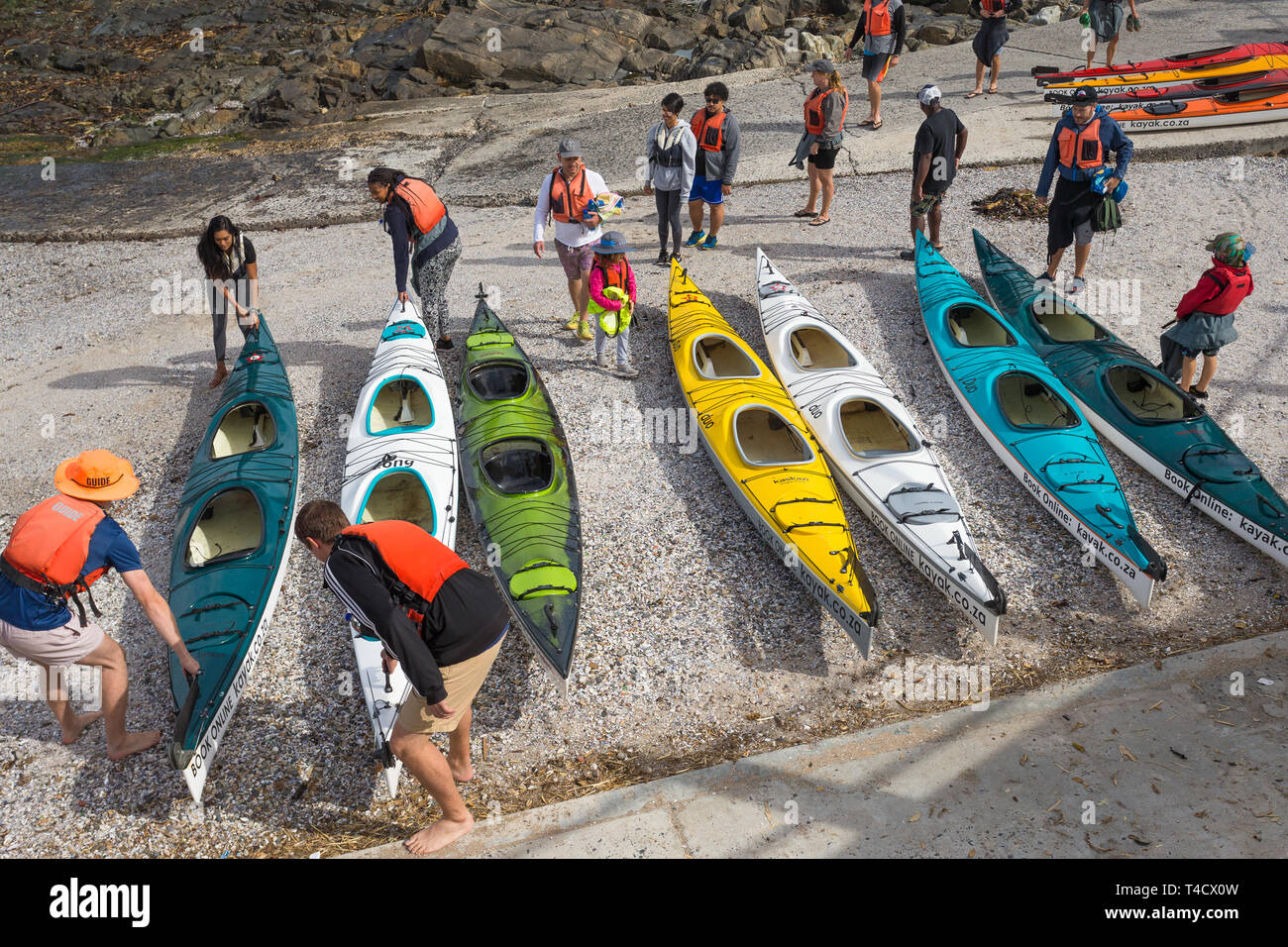 Groupe de touristes recueillir leurs kayaks colorés de la plage de transporter jusqu'à la mer ou l'océan au Cap, Afrique du Sud, au cours des vacances Banque D'Images