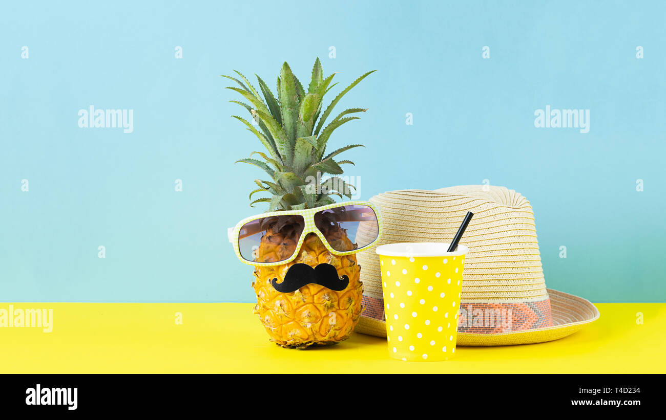 Funny habillés dans des verres d'ananas avec une moustache noire, un chapeau de paille avec un verre en verre jaune vif d'un fond bleu. Banque D'Images