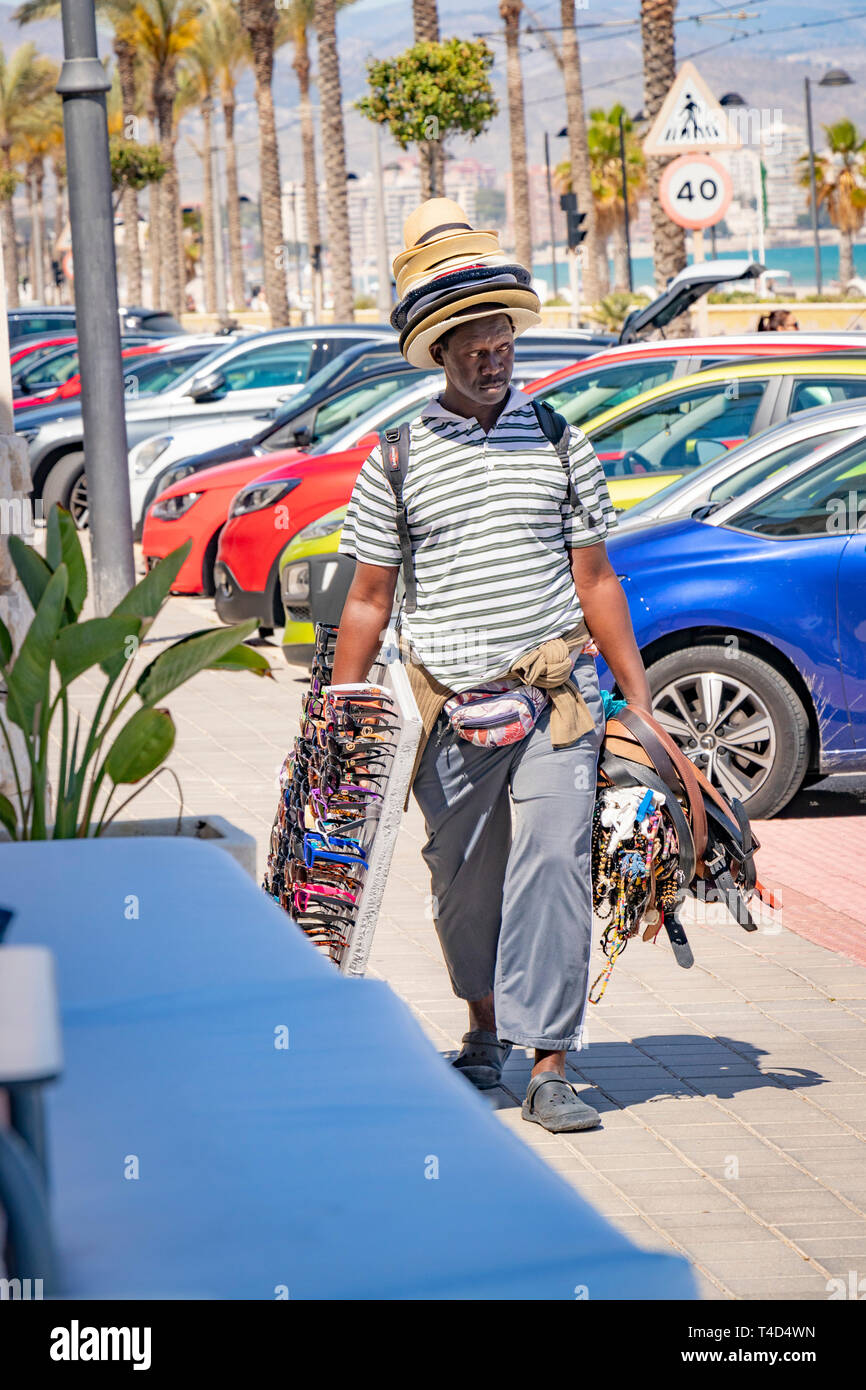 Homme accablé avec des chapeaux et des cadeaux pour la vente sur la plage d''Alicante Banque D'Images