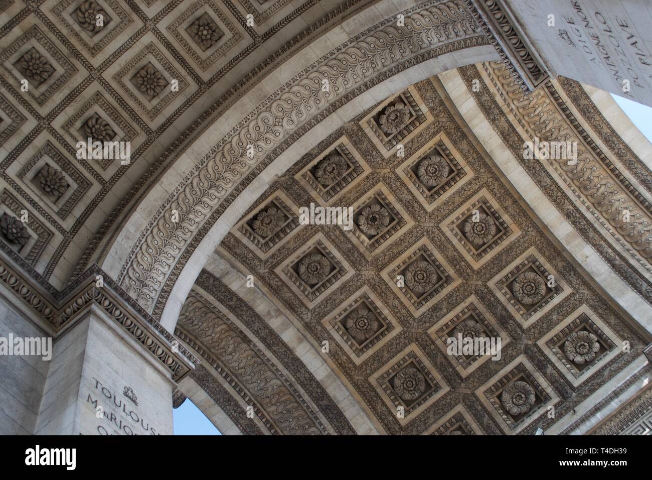 Les patrons et fleurs sculptées dans la pierre du toit de l'Arc de Triomphe à Paris, France. Passage voûté et sur les places ; aperçu de ciel bleu sur les côtés. Banque D'Images