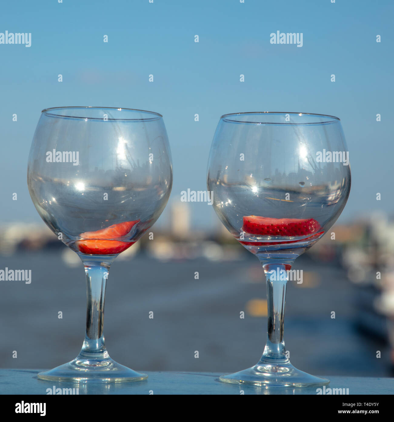 Deux verres vides avec un morceau de fraise dans chaque sur le côté gauche de la Tower Bridge, enjambant la rivière Thames, London, England, UK. Banque D'Images