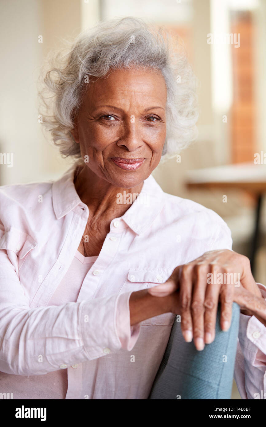 Portrait Of Smiling Senior Woman Relaxing On Sofa At Home Banque D'Images