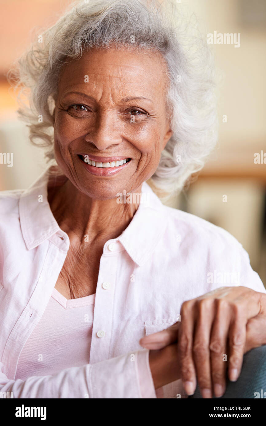 Portrait Of Smiling Senior Woman Relaxing On Sofa At Home Banque D'Images