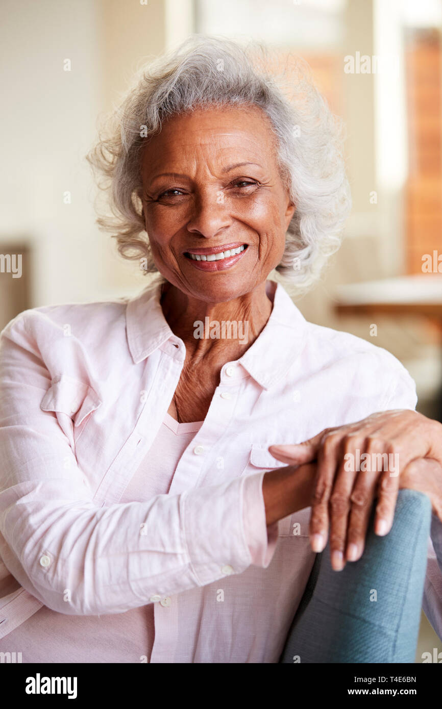 Portrait Of Smiling Senior Woman Relaxing On Sofa At Home Banque D'Images
