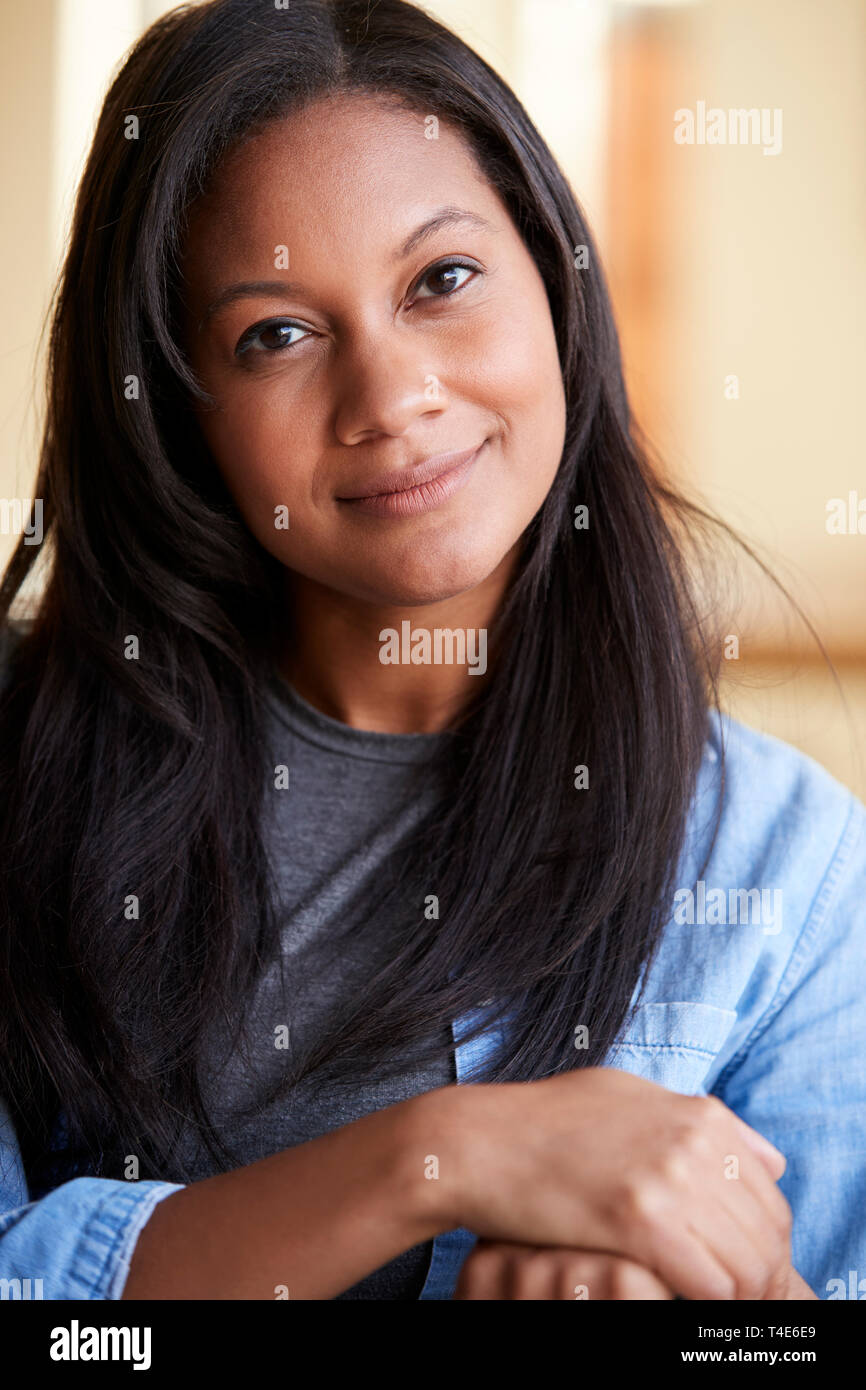 Portrait Of Smiling Woman sitting on Sofa At Home Banque D'Images