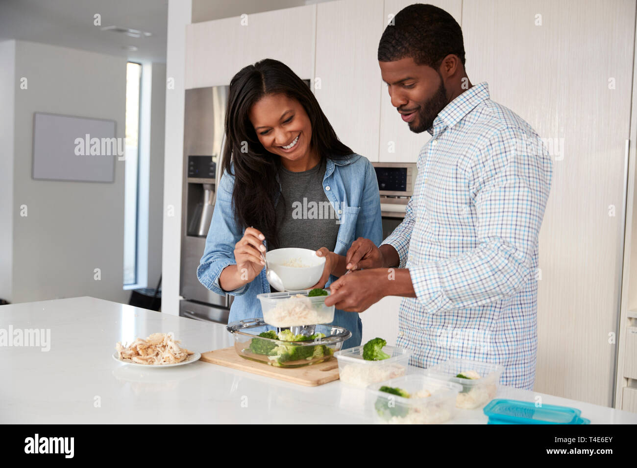 Couple dans la cuisine préparer le repas à haute teneur en protéines et de mettre dans des contenants en plastique Banque D'Images