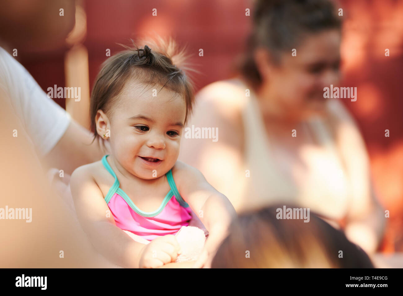 Portrait of baby girl sur grand-parent les mains sur l'arrière-plan arrière-cour ensoleillée Banque D'Images