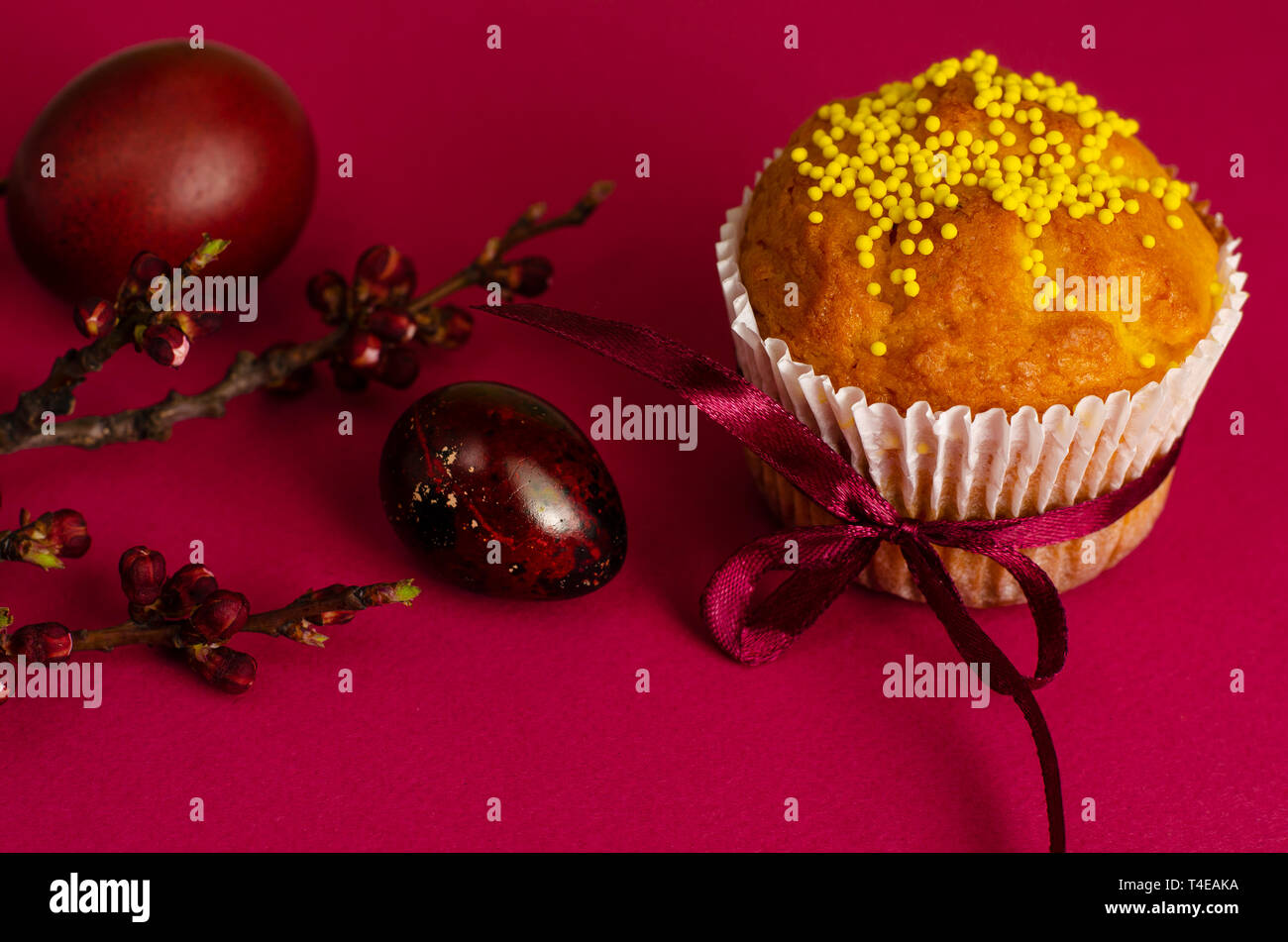 Muffins de pâques décorés avec du ruban et des Sprinkles, les oeufs colorés et une branche d'arbre d'abricot sur un fond rose ou fuchsia. Copier l'espace. Greetin Banque D'Images