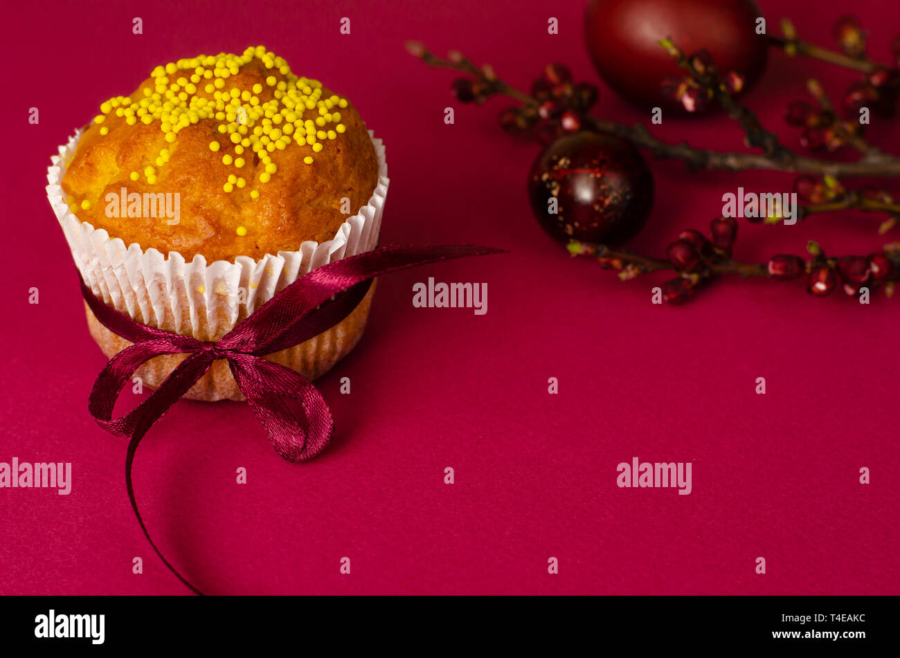 Muffins de pâques décorés avec du ruban et des Sprinkles, les oeufs colorés et une branche d'arbre d'abricot sur un fond rose ou fuchsia. Copier l'espace. Greetin Banque D'Images
