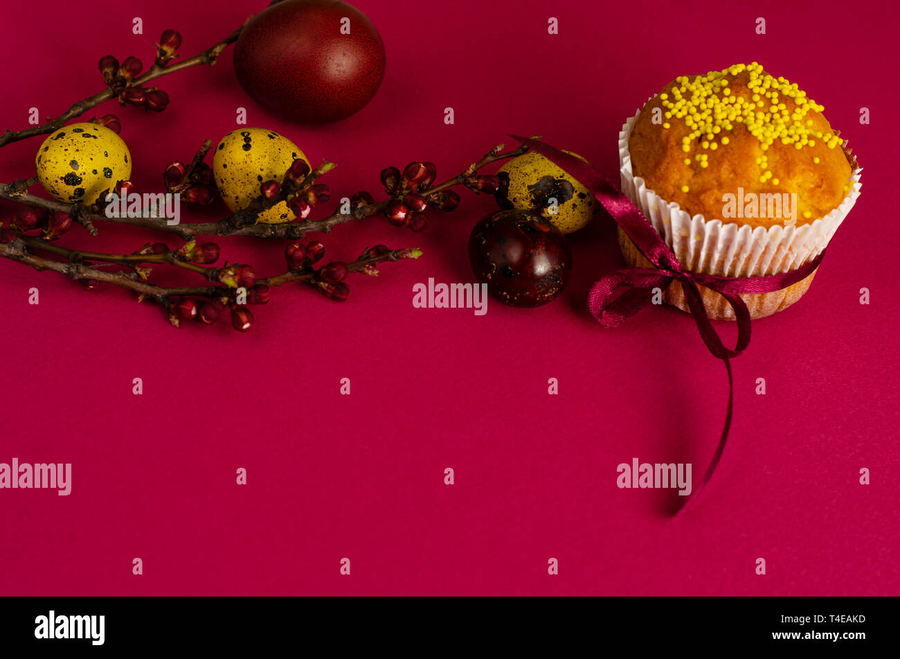 Muffins de pâques décorés avec du ruban et des Sprinkles, les oeufs colorés et une branche d'arbre d'abricot sur un fond rose ou fuchsia. Copier l'espace. Greetin Banque D'Images