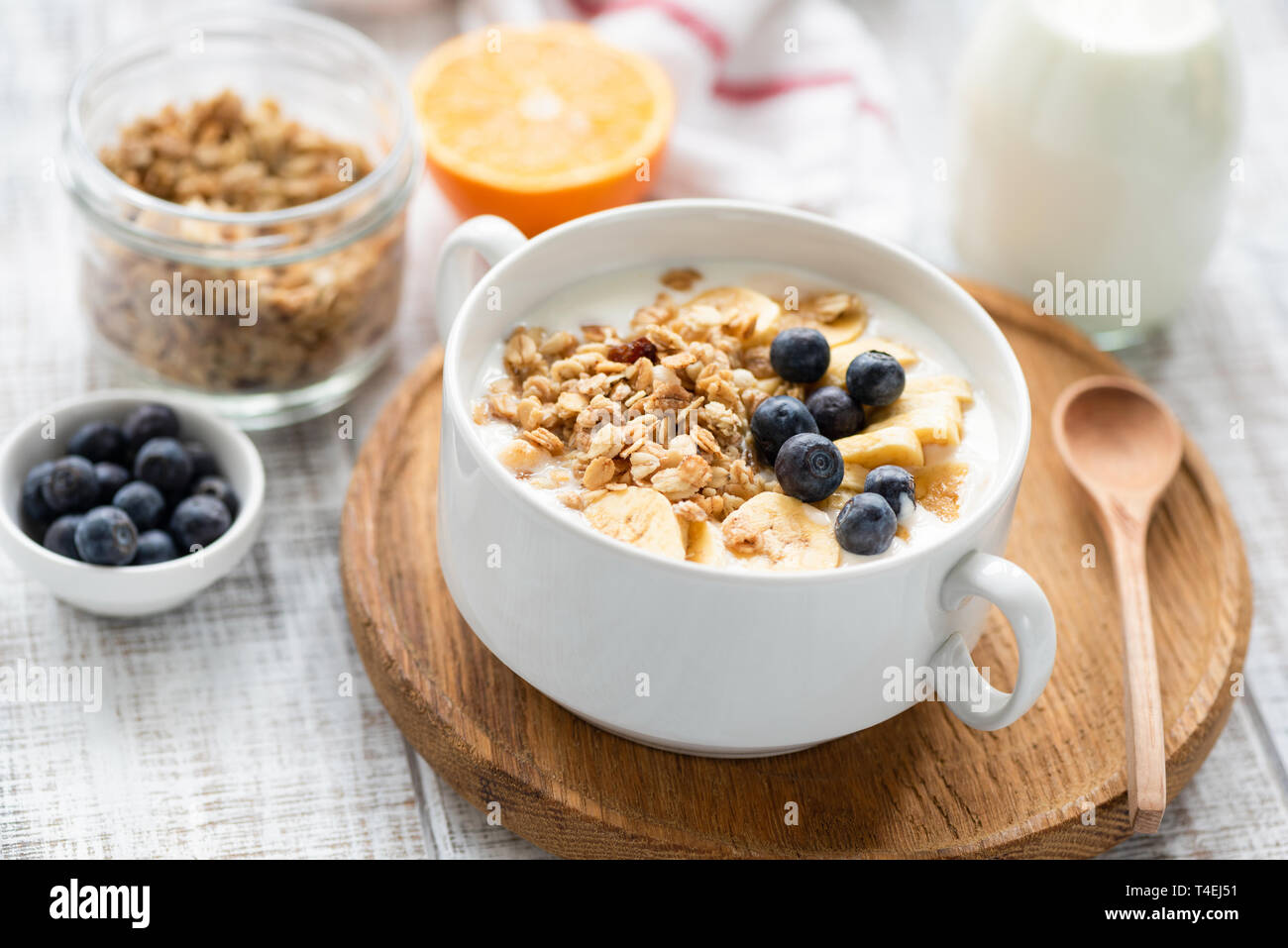 Les céréales de petit-déjeuner sain le muesli avec du lait et des fruits dans un bol sur la table en bois. Vue rapprochée, selective focus Banque D'Images
