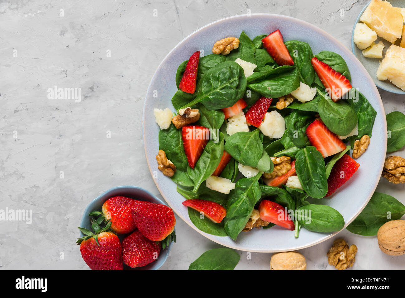 Avec salade de fraises, épinards, parmesan et noix sur fond de béton. alimentation saine alimentation. top view with copy space Banque D'Images
