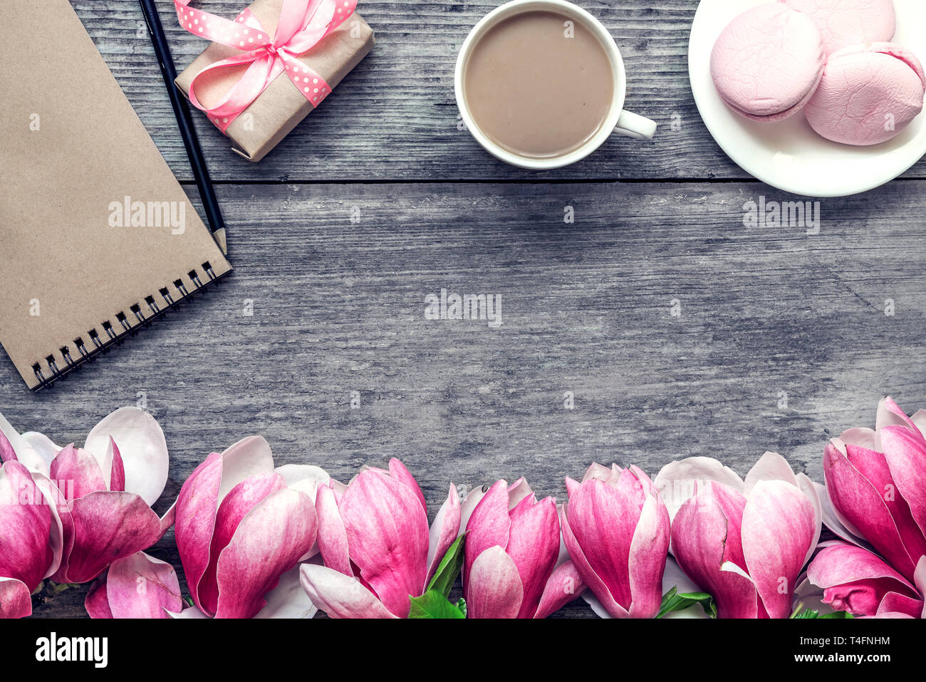 Tasse de café avec du lait, gâteau macaron, cadeau ou présent fort et magnolia fleurs sur table en bois rustique. Télévision. vue d'en haut. printemps maison de bre Banque D'Images