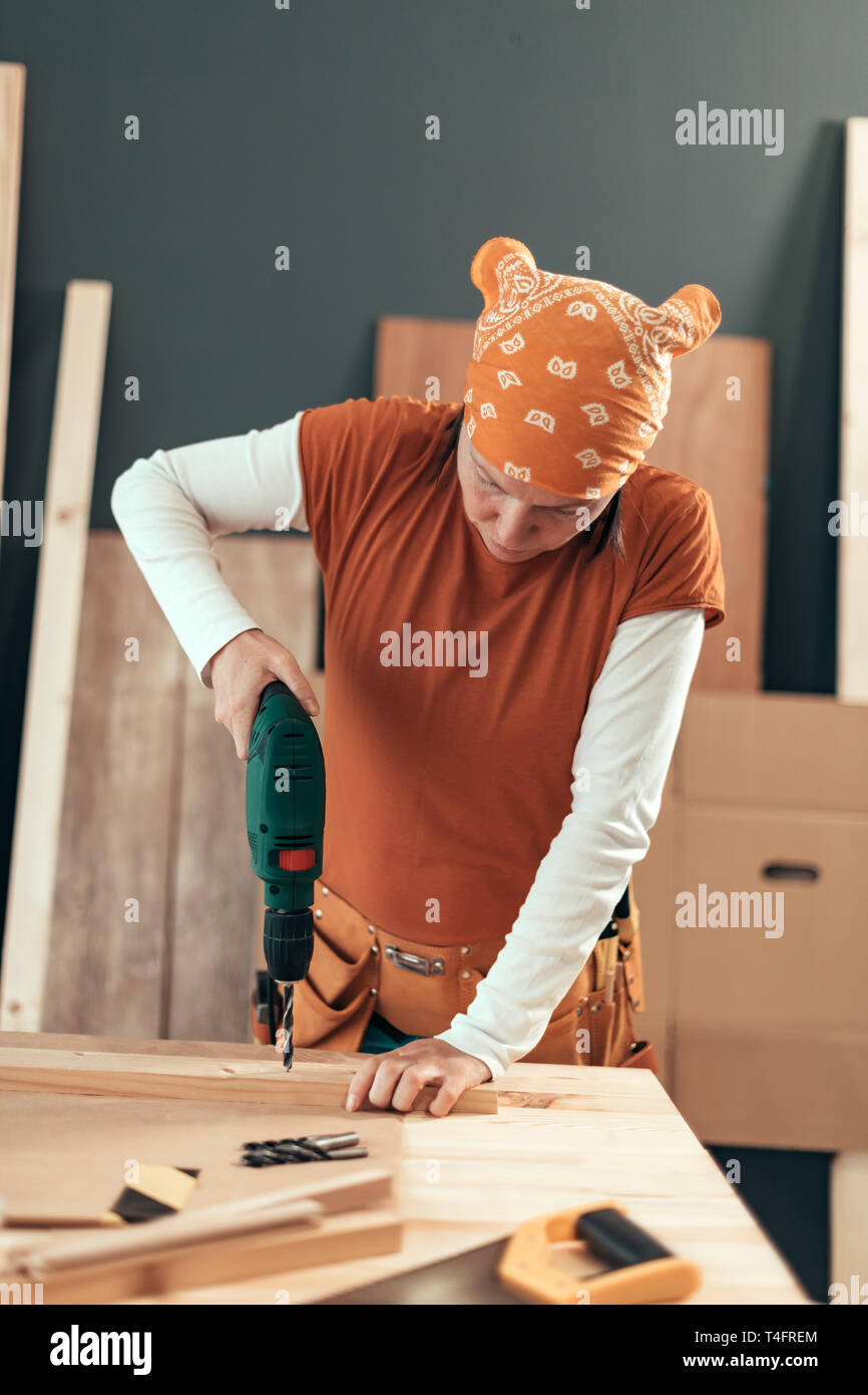 Female carpenter en utilisant la perceuse électrique en atelier de menuiserie ébénisterie, selective focus Banque D'Images