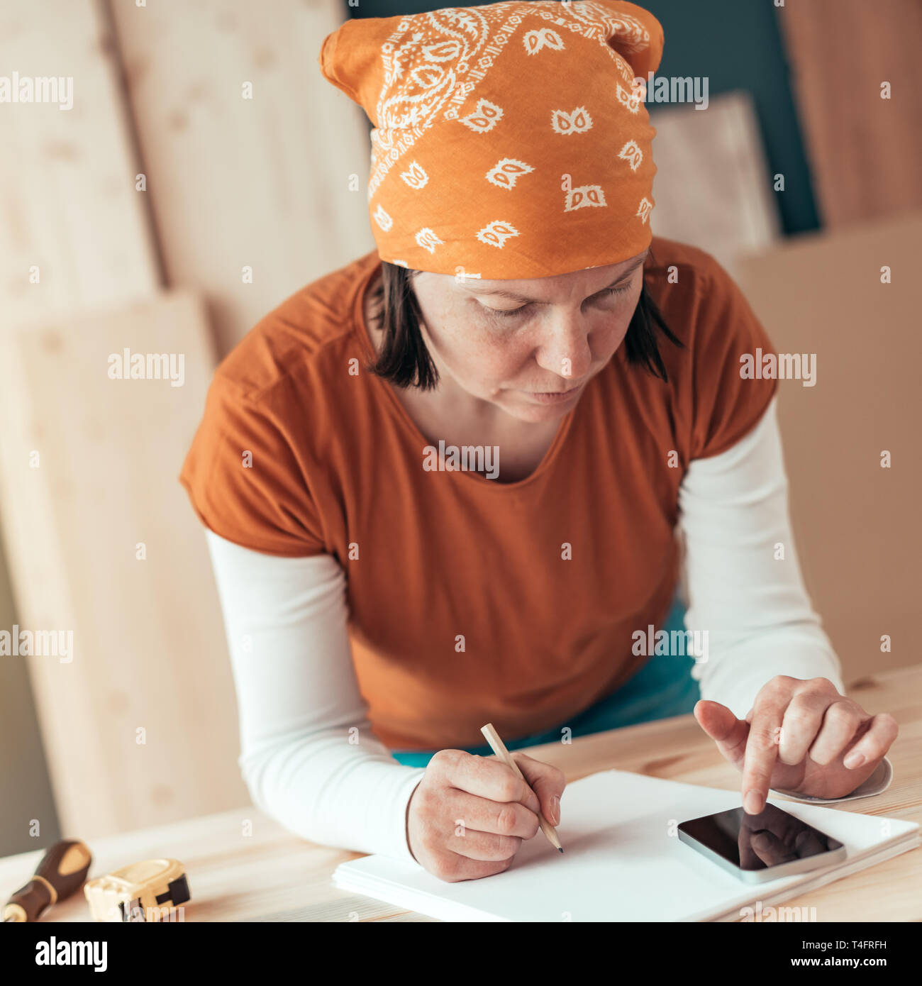 Female carpenter avec foulard tête faisant calcul financier dans l'atelier de menuiserie menuiserie Banque D'Images