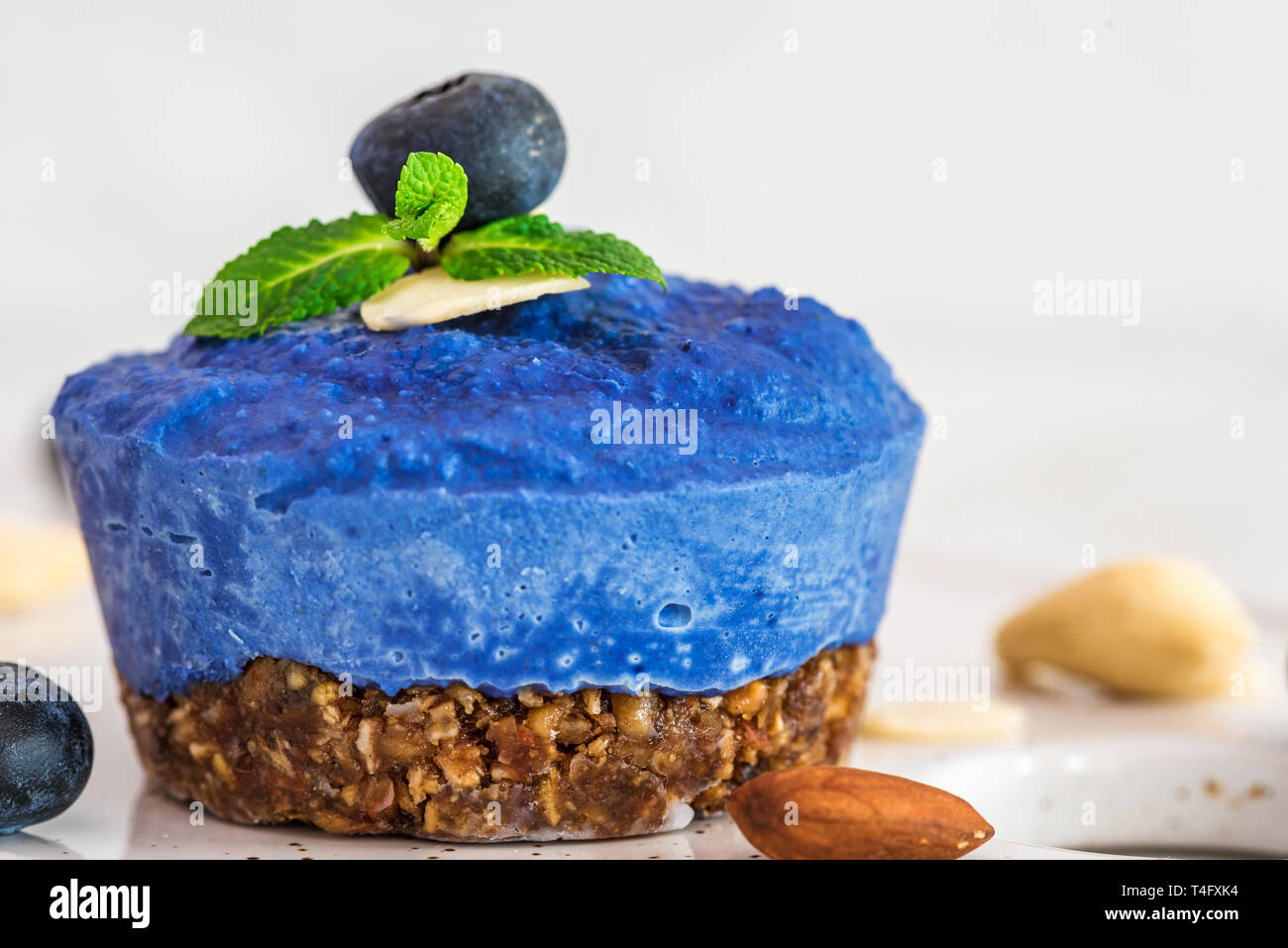 Matières de bleuet, l'açaï et papillon fleur Pois vegan gâteau avec les baies fraîches, menthe, noix. La nourriture végétalienne saine concept. close up Banque D'Images