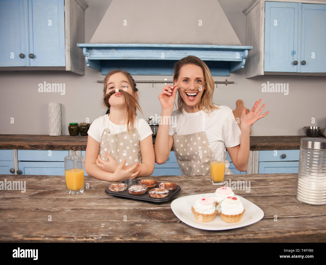 Heureux famille aimante dans la cuisine. Mère et enfant fille fille mangent des cookies qu'ils ont fait et d'avoir du plaisir dans la cuisine faire des grimaces. Banque D'Images