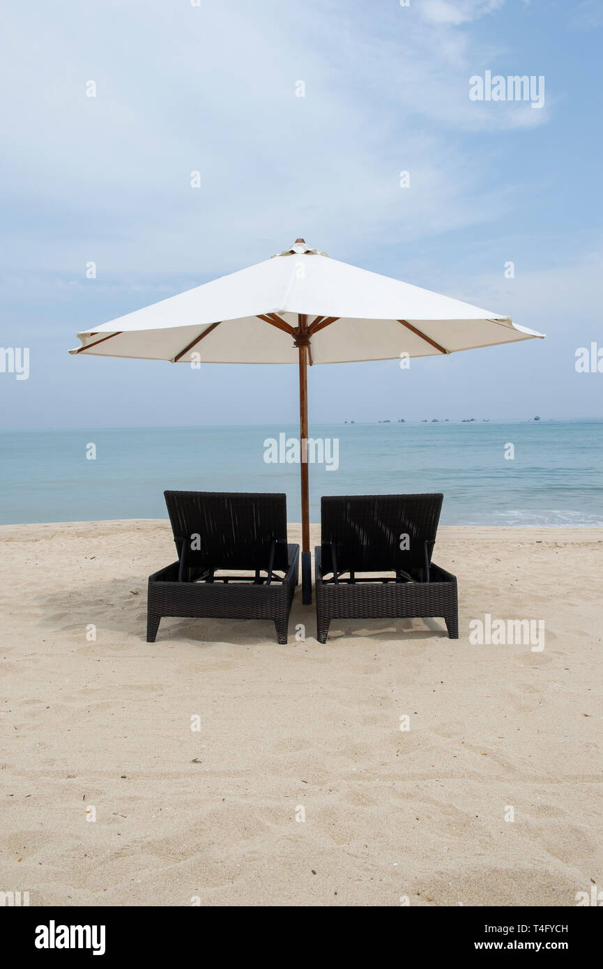 Deux chaises longues avec un parasol sur la plage de Jimbaran, Bali, Indonésie Banque D'Images