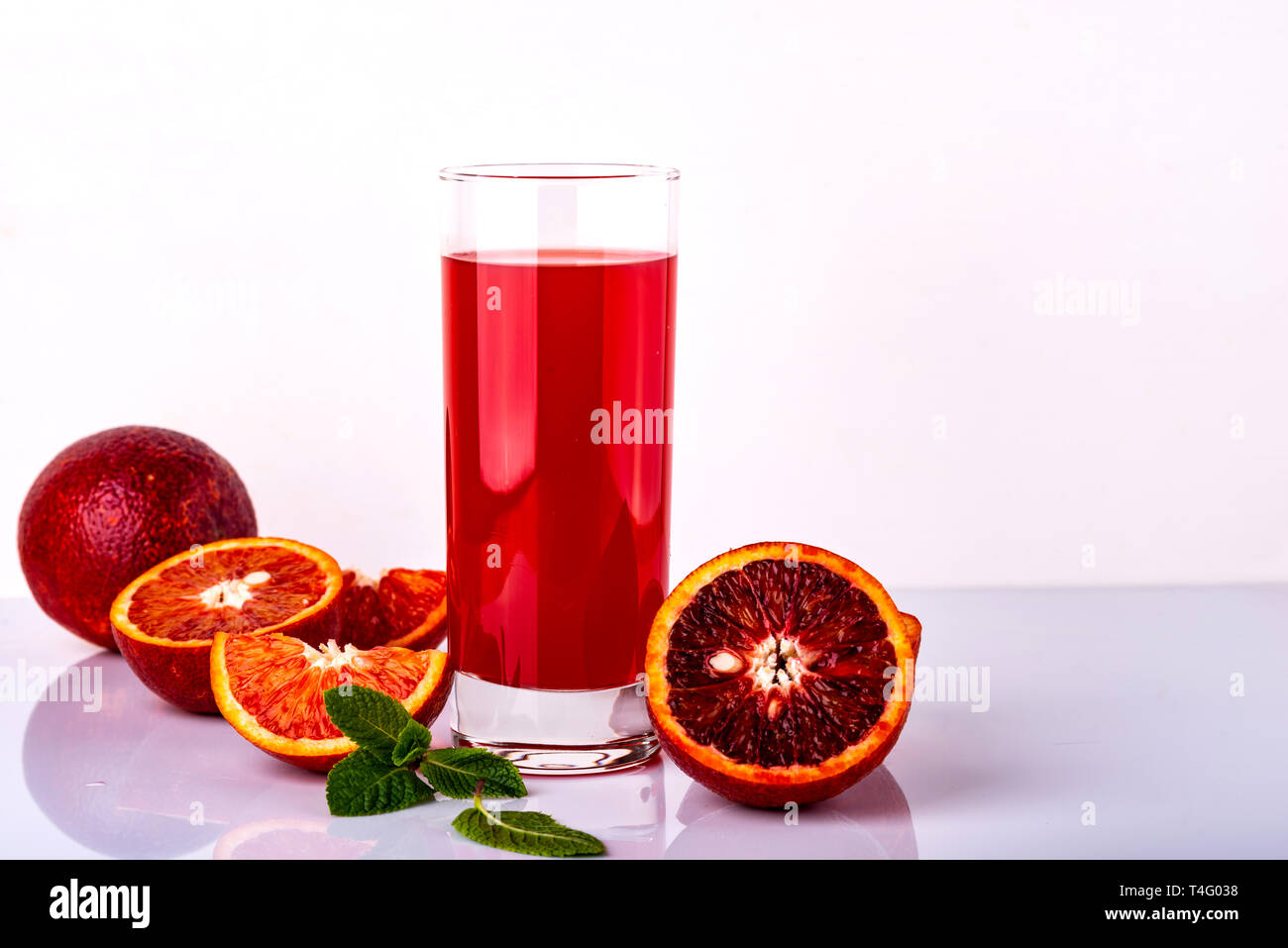 Avec un verre de jus d'orange de Sicile quelques morceaux sur un fond blanc. Boisson à l'orange de Sicile. Banque D'Images