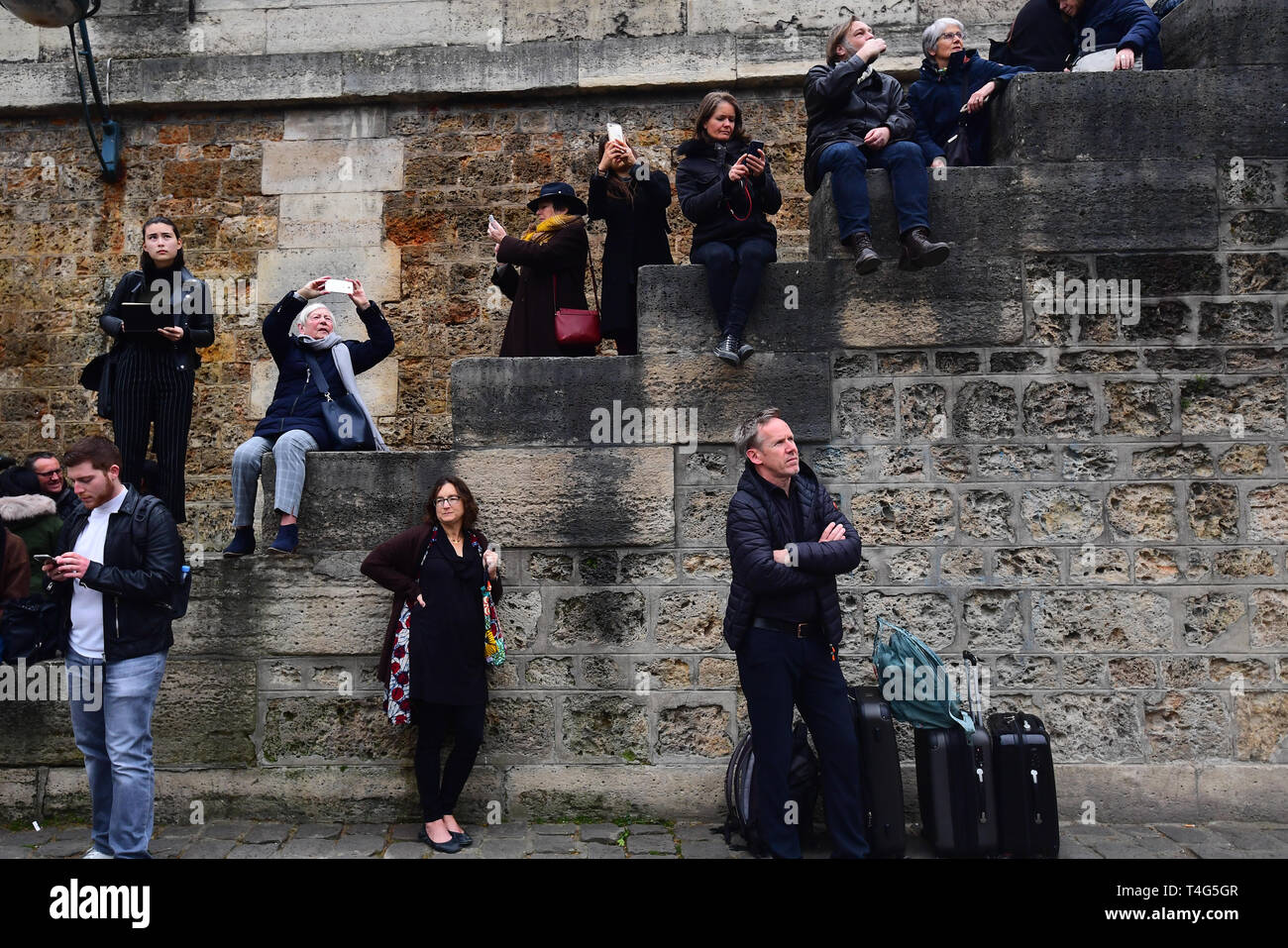 Une foule de personnes regarder vers le reste de la Cathédrale Notre Dame de Paris à la suite d'un incendie qui détruit une grande partie de l'immeuble dans la soirée de lundi. Banque D'Images