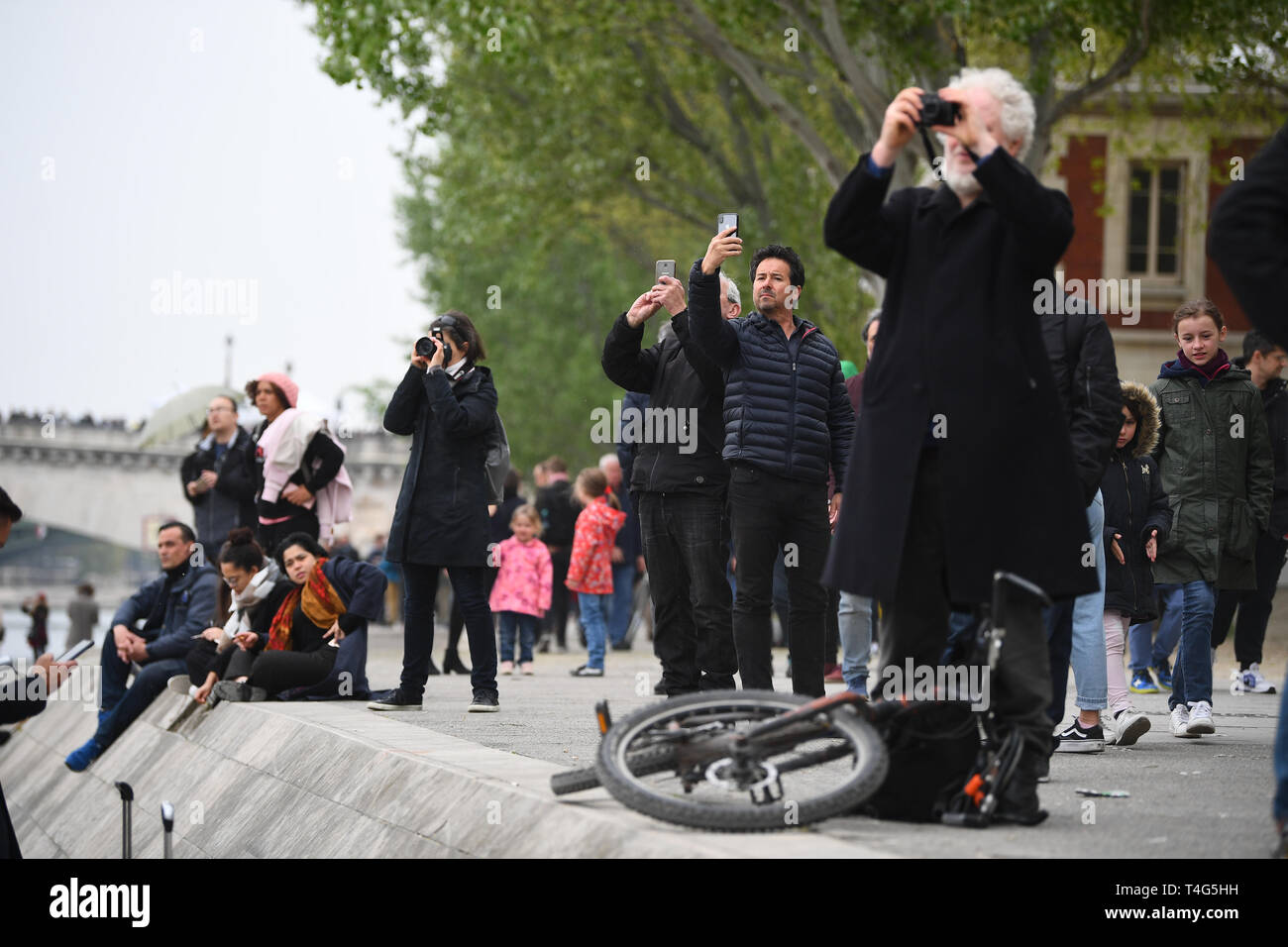 Une foule de personnes de regarder et prendre des photos des vestiges de la Cathédrale Notre Dame de Paris à la suite d'un incendie qui détruit une grande partie de l'immeuble dans la soirée de lundi. Banque D'Images