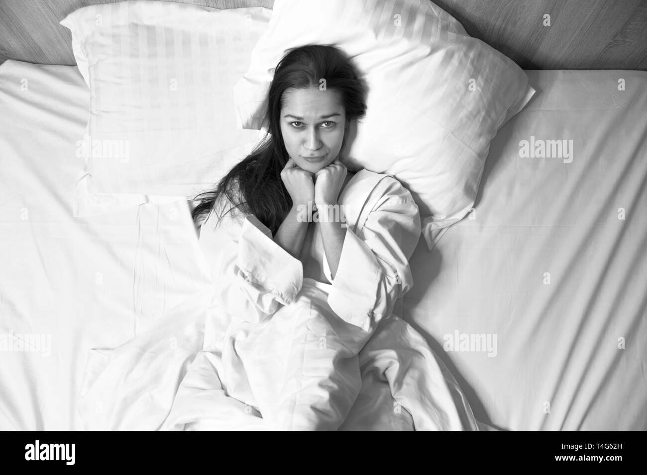 Happy young brunette woman in bed Banque D'Images