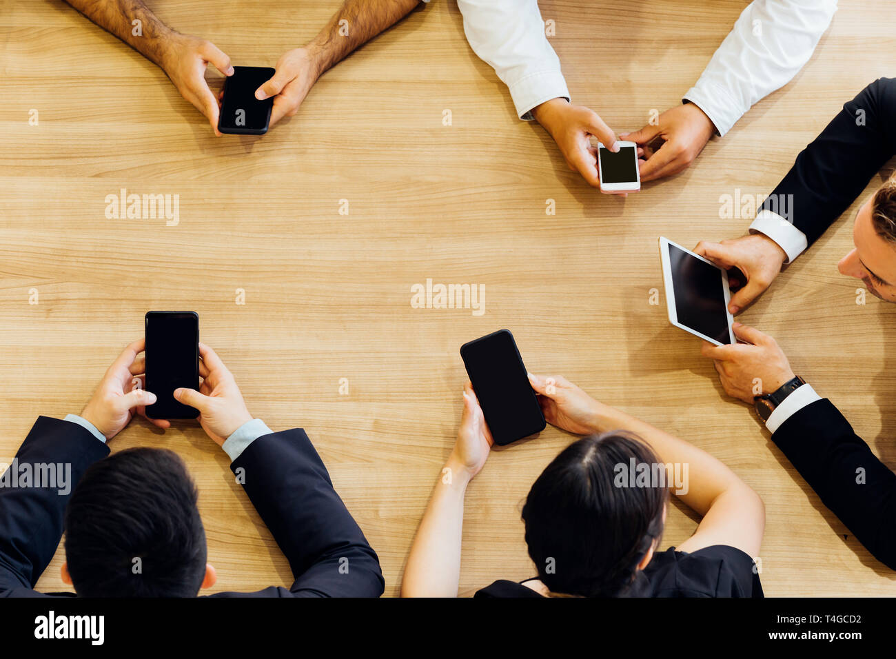 À partir de la récolte au-dessus des hommes et femmes d'affaires officielles assis en cercle au tableau et l'utilisation de téléphones mobiles dans office Banque D'Images