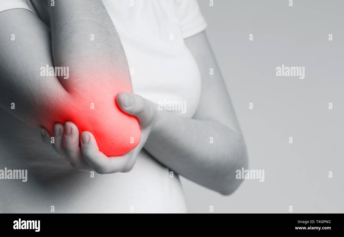 Des douleurs osseuses ou musculaires autour de coude, femme tenant la main enflammée, photo monochrome Banque D'Images