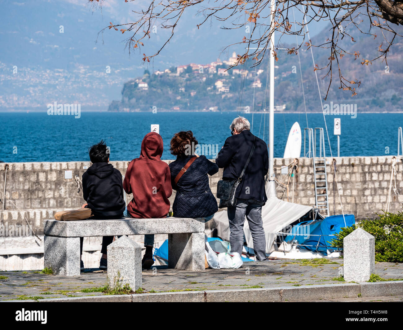 Image de la famille assise sur un banc en pierre de derrière et le lac majeur à l'arrière-plan Banque D'Images