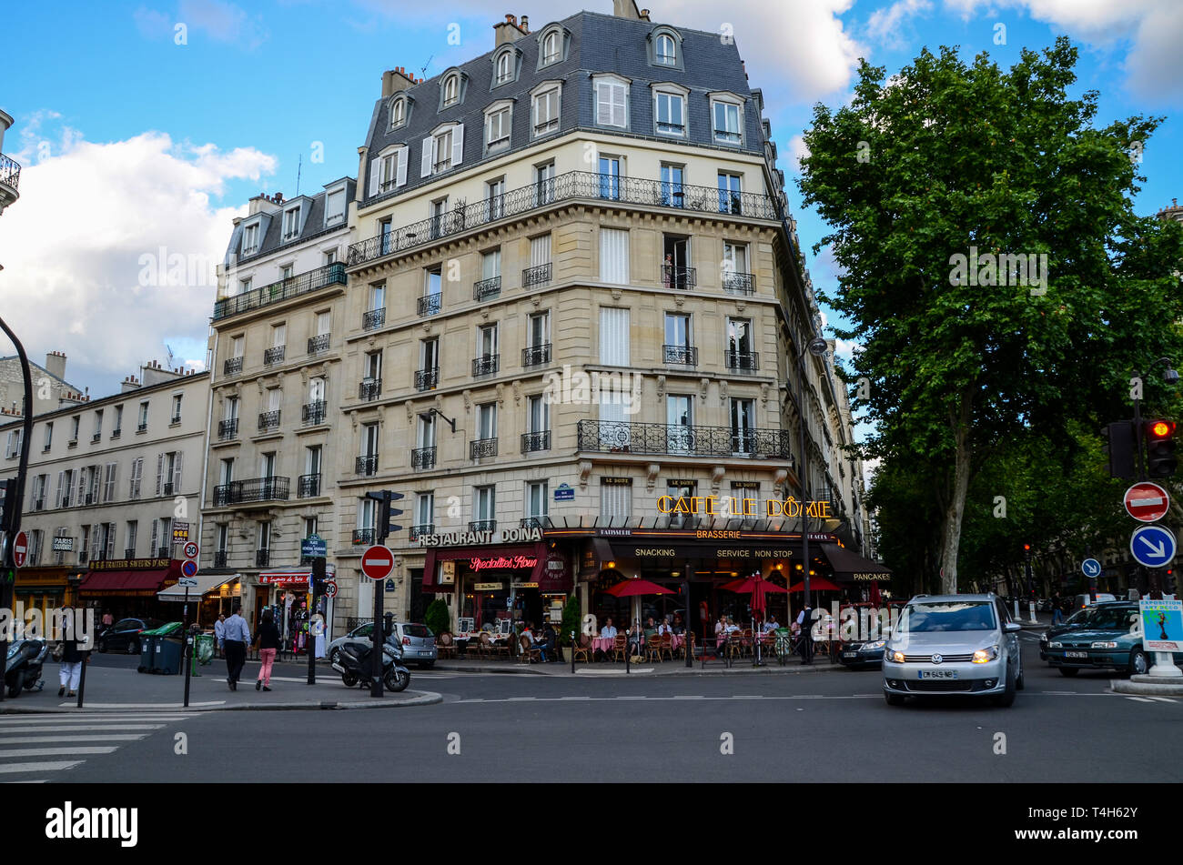 Café le Dome, Paris, France. Les clients manger à l'extérieur, de manger dehors en soirée, à la tombée de la nuit. Restaurant Doina. Trottoir. Personnes et de trafic Banque D'Images