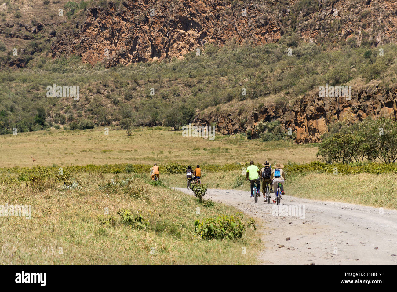 Les touristes avec la bicyclette guide sur une route poussiéreuse, Hells Gate National Park, Kenya Banque D'Images