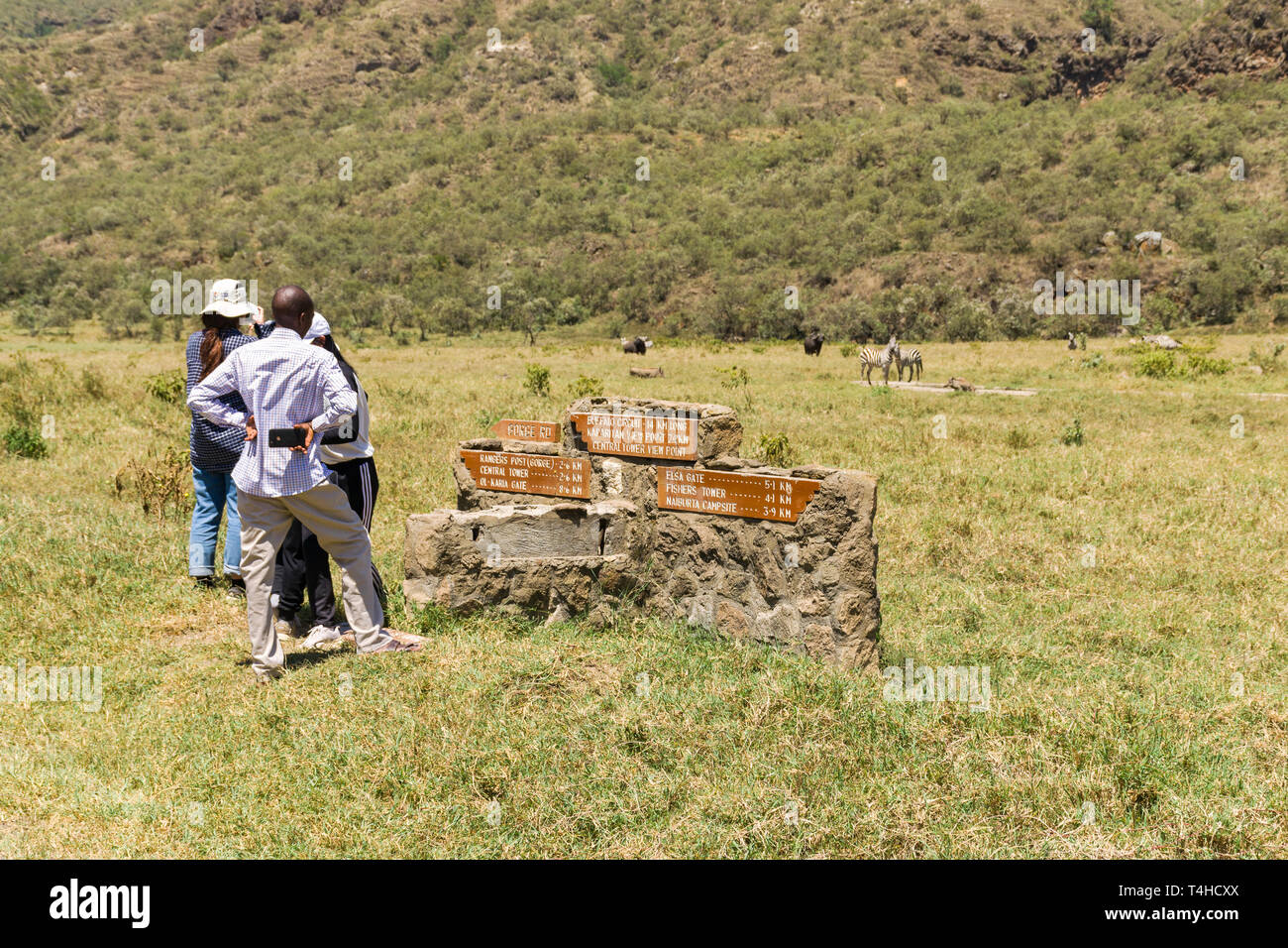 Les touristes debout près de Stone Road sign à la faune, à Hells Gate National Park, Kenya Banque D'Images