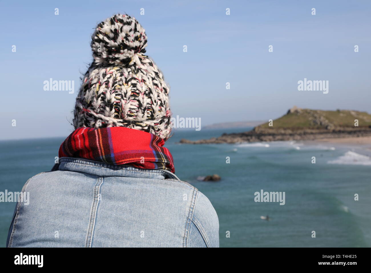 Girl looking out to sea enveloppé avec woolly hat Banque D'Images