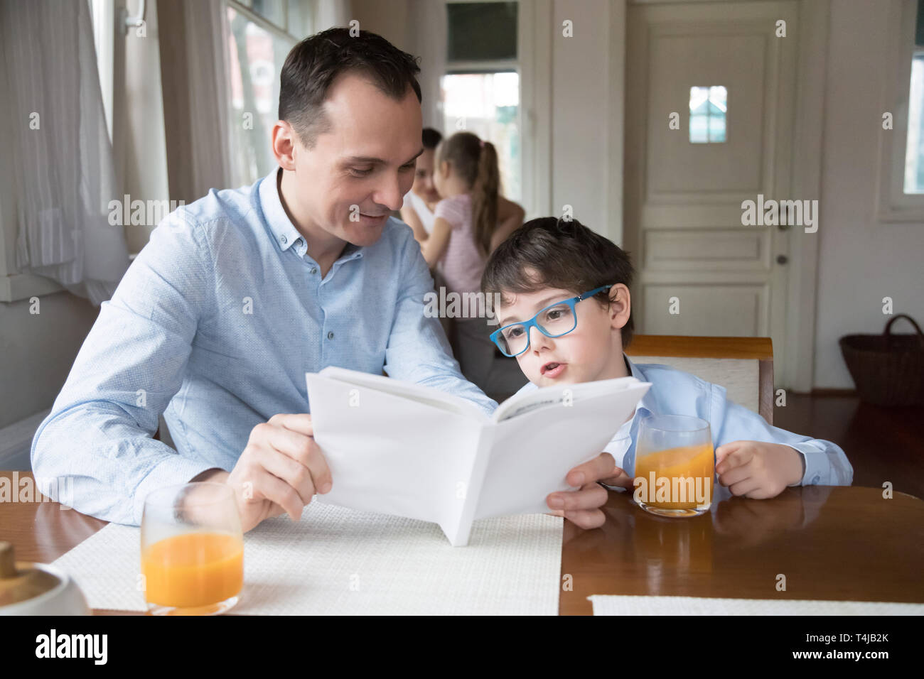 Père et fils lecture livre ensemble salle à manger à Banque D'Images