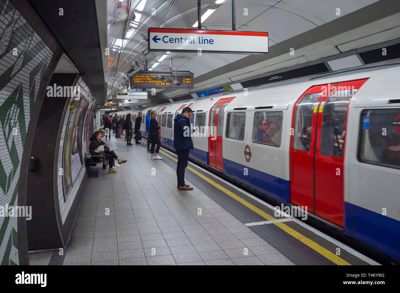 Les banlieusards attendre sur la plate-forme pour passer à une ligne centrale du tube, à la station de métro de Waterloo, Londres Banque D'Images