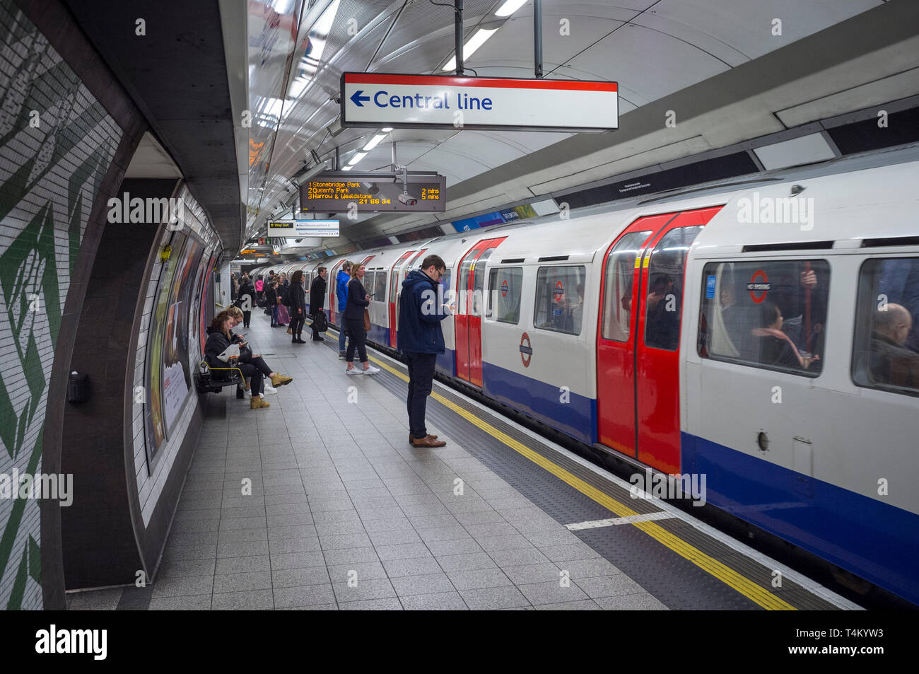 Les banlieusards attendre sur la plate-forme pour passer à une ligne centrale du tube, à la station de métro de Waterloo, Londres Banque D'Images