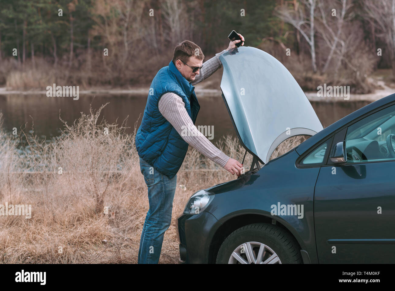 Les jeunes bel homme ayant problème avec voiture et appeler à l'aide. Banque D'Images