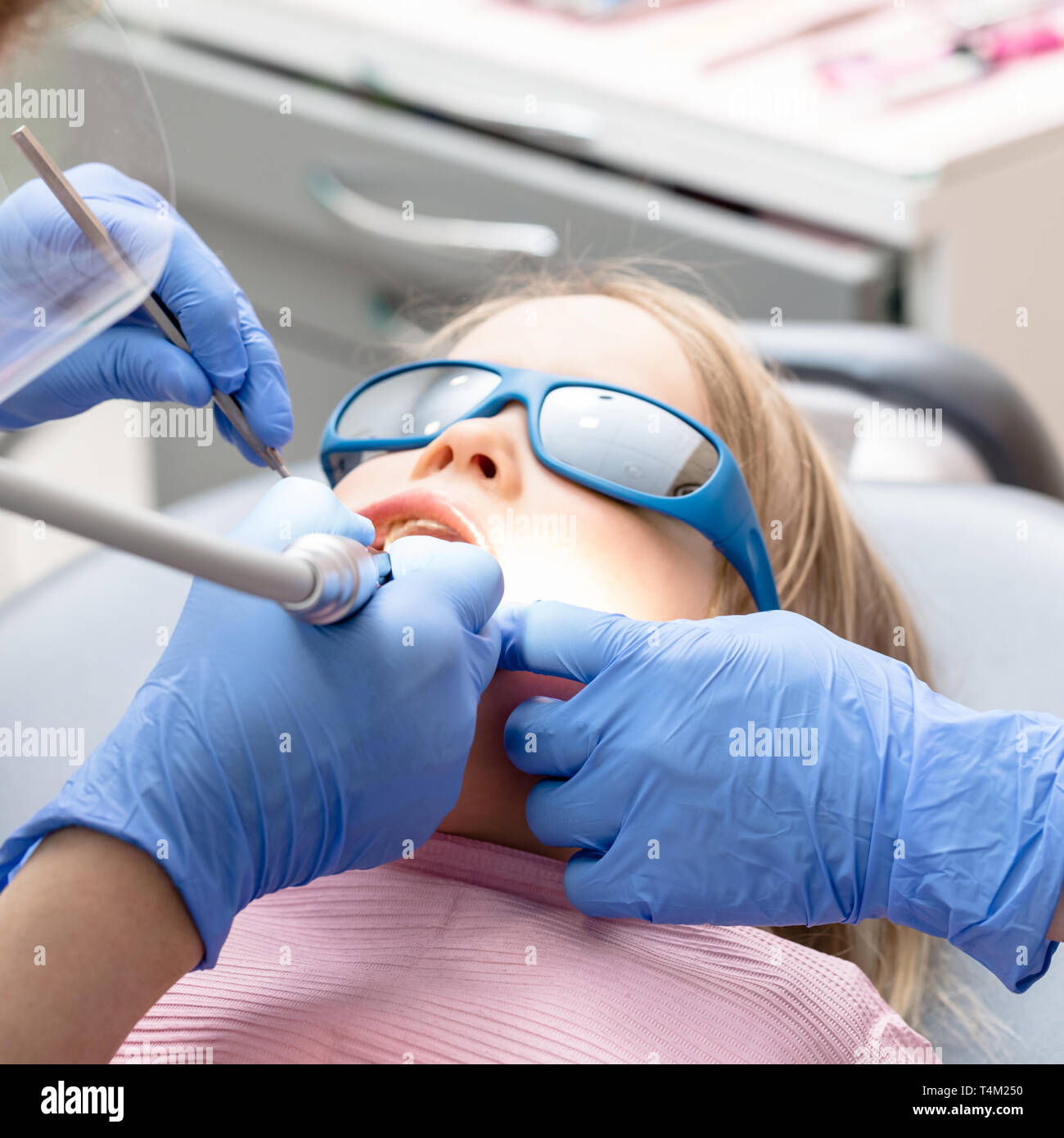 Effectuer la procédure de remplissage dentaire dentiste pour une petite fille à la clinique de dentisterie pédiatrique. Médecin de retirer à l'aide de caries dentaires à haute vitesse. Calme ch Banque D'Images
