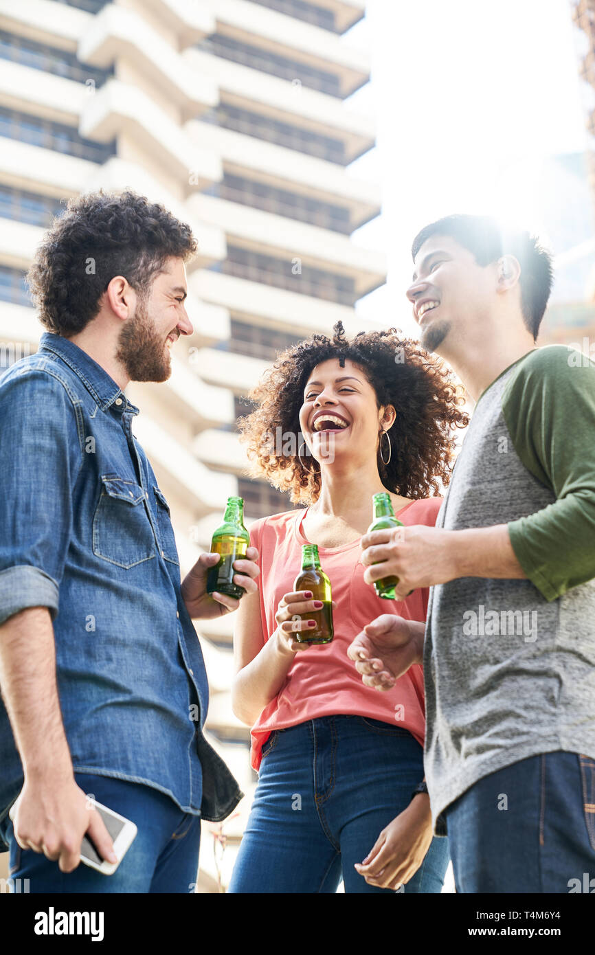 Trois amis rire boire de la bière ensemble sur un toit de maison dans la ville Banque D'Images