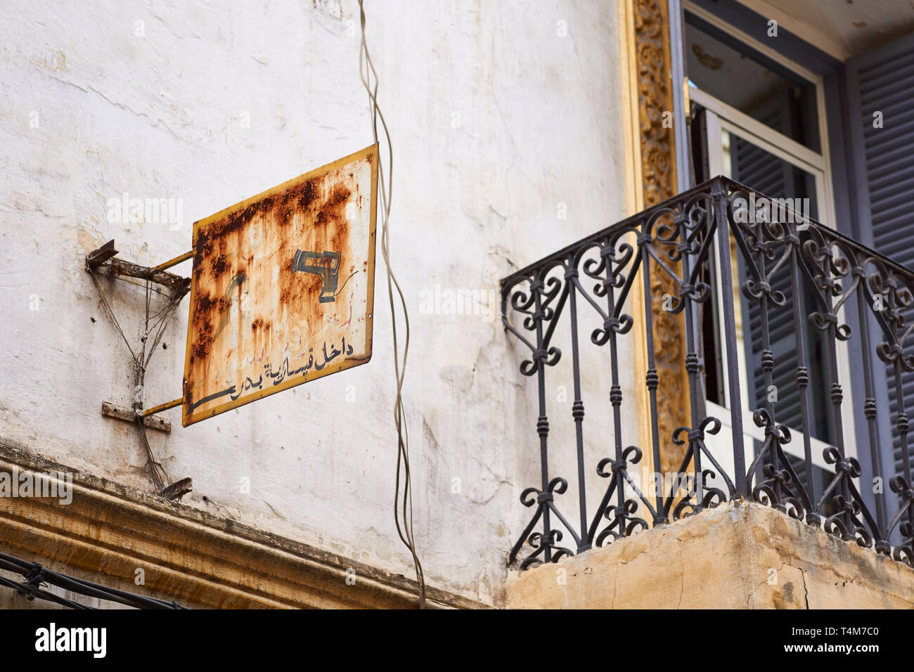 Rusty old coiffure boutique sign en arabe écrit et un balcon à Tanger, Maroc Banque D'Images