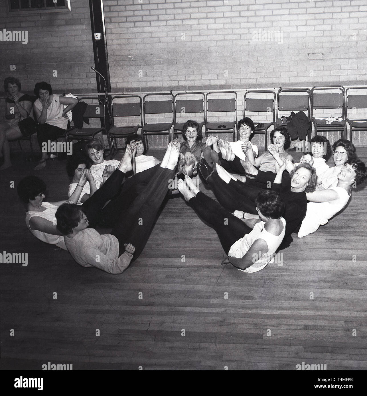 Annes 1960, historique, un groupe de professionnels chers dans leurs  jambires sur le sol faire une classe de yoga ou de garder la forme  la  salle de sport locale. Deux dames