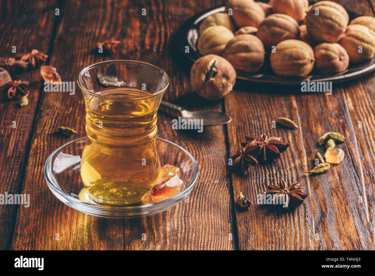Thé Oriental avec l'anis étoilé, de cardamome et de chaux séchée dans armudu verre au-dessus de la surface en bois Banque D'Images