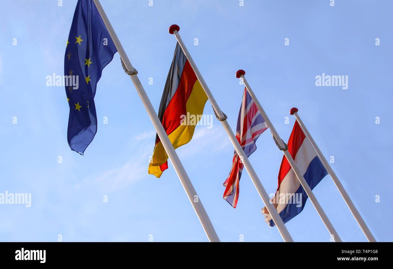 Les drapeaux de l'Angleterre, Royaume-Uni, Allemagne et Nederlands waving from mâts en coopération avec l'Europe, l'Union européenne, d'un drapeau contre un ciel bleu. Banque D'Images