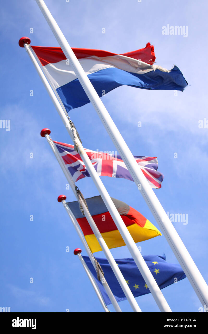 Les drapeaux de l'Angleterre, Royaume-Uni, Allemagne et Nederlands waving from mâts en coopération avec l'Europe, l'Union européenne, d'un drapeau contre un ciel bleu. Banque D'Images