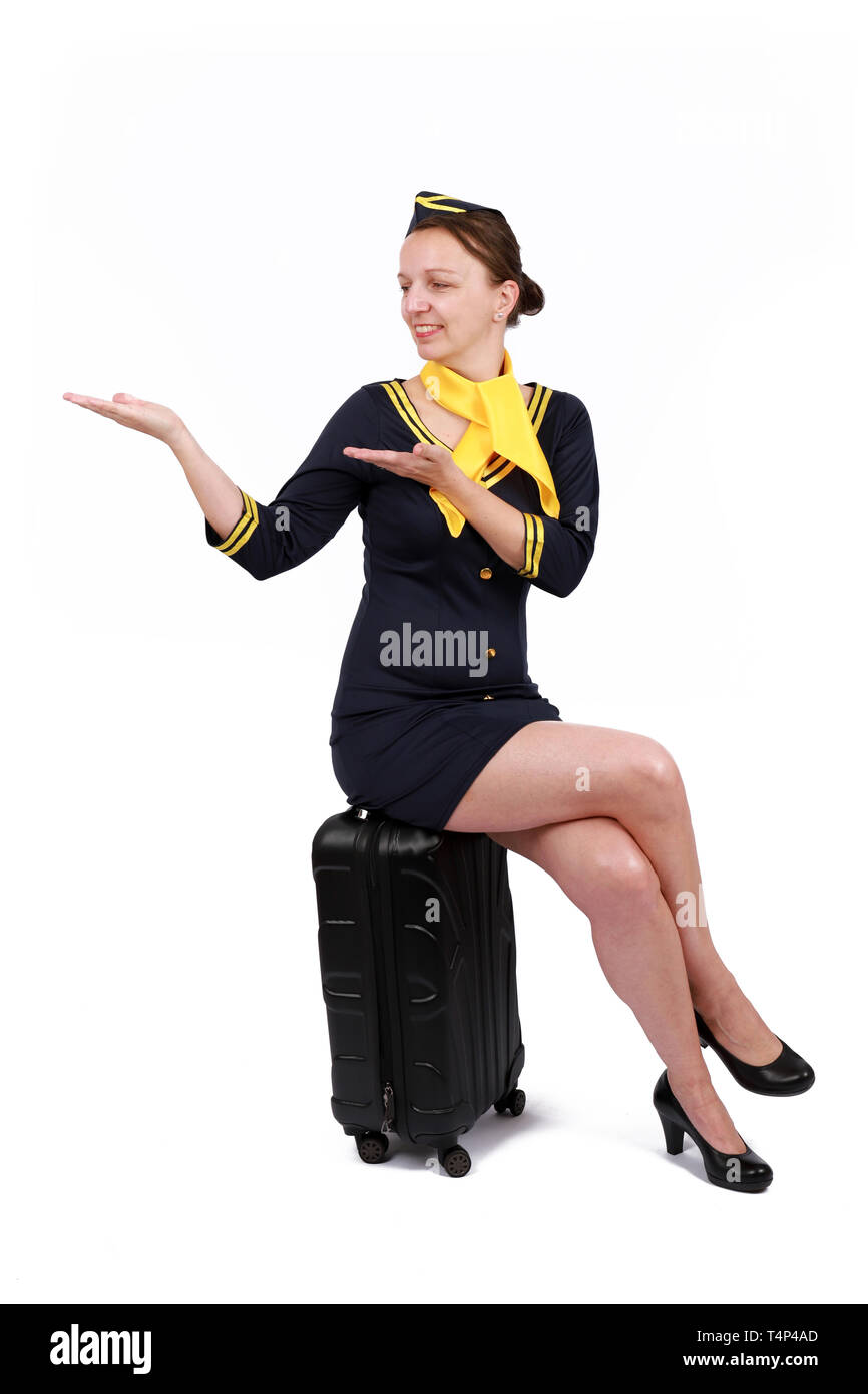 - Stewardesse et charmante hôtesse souriante habillés en uniforme bleu assis sur sa valise . Isolé sur fond blanc Banque D'Images
