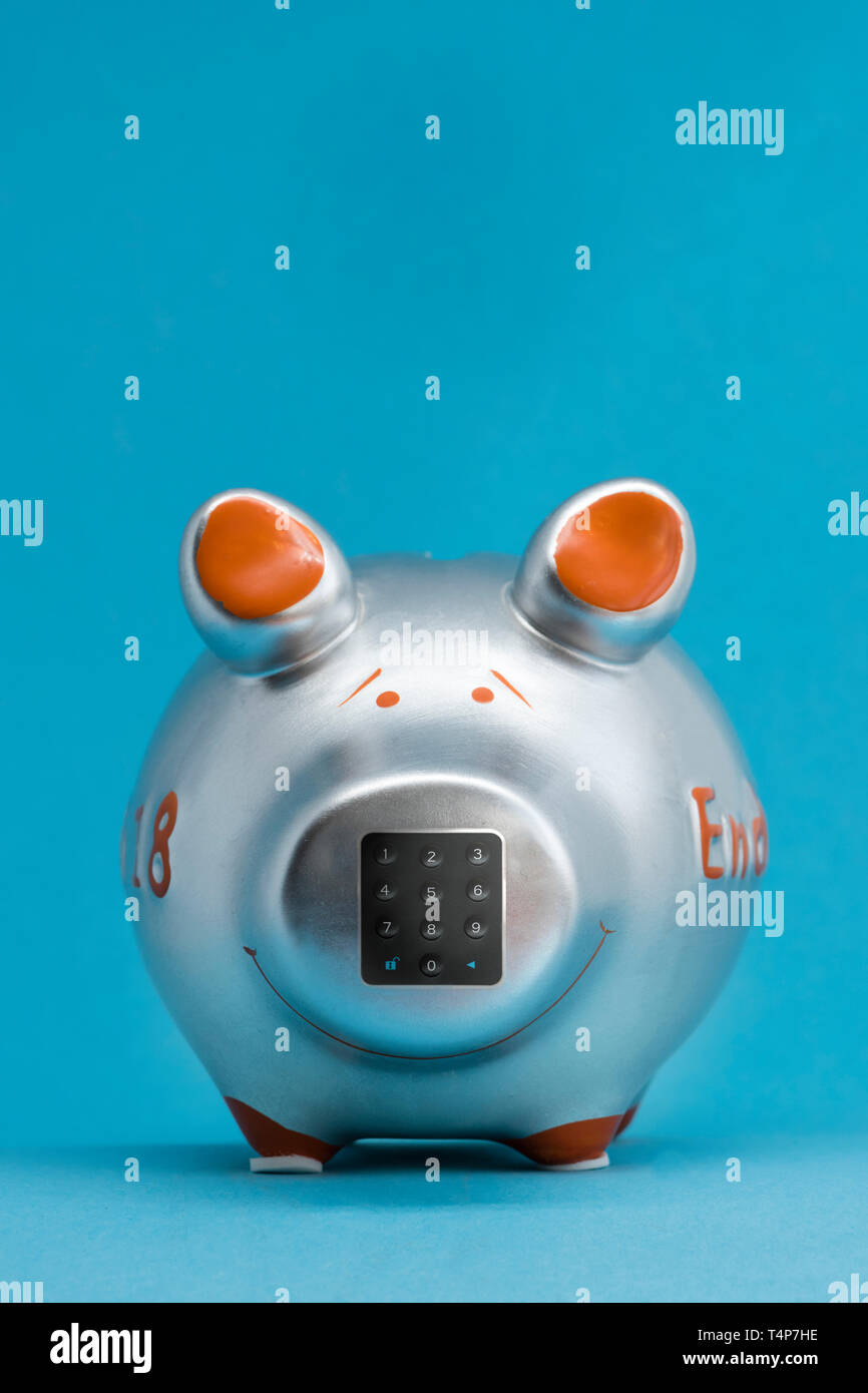 Tirelire couleur métallisée sur fond bleu avec un clavier numérique pour la saisie de code PIN sur le nez de cochon. (Manipulé) Banque D'Images