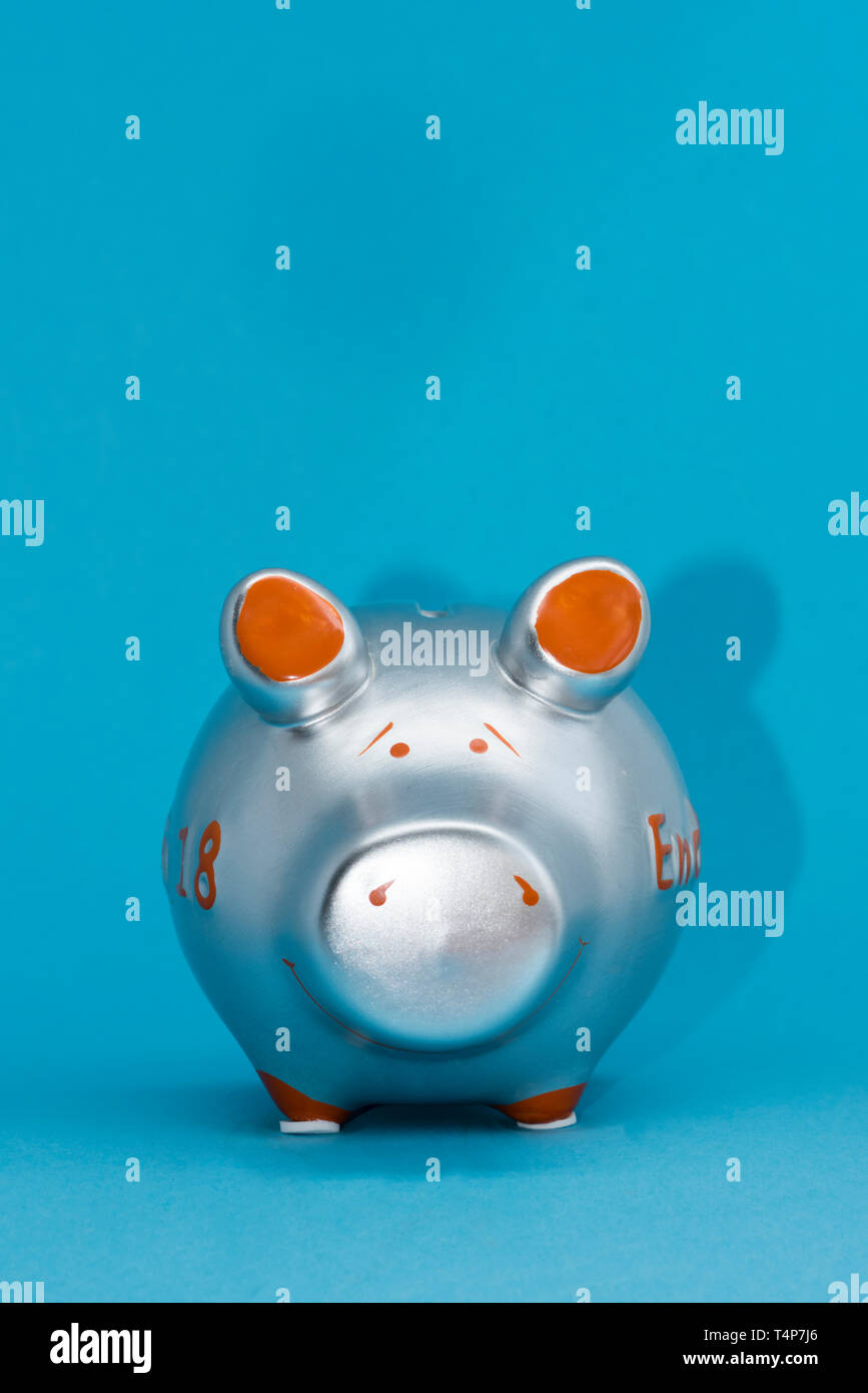 Tirelire couleur métallisée sur fond bleu, quelque peu sceptique. Banque D'Images