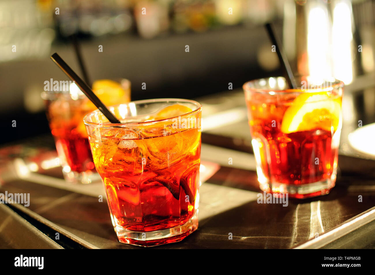 Trois verres de cocktails glacés avec paille et tranche de citron ou  d'orange sur un comptoir bar avec angle incliné vers l'un à l'avant-plan  Photo Stock - Alamy